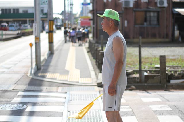 炎天下で三条市で下校する嵐南小児童を見守る男性
