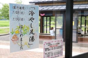 道の駅 国上の足湯「酒呑童子の湯」の冷やし足湯をPRするちらし、奥に見えるのが足湯