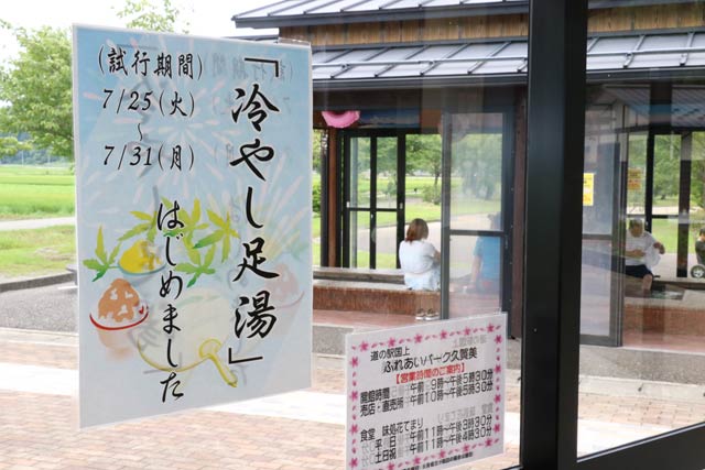  道の駅 国上の足湯「酒呑童子の湯」の冷やし足湯をPRするちらし、奥に見えるのが足湯