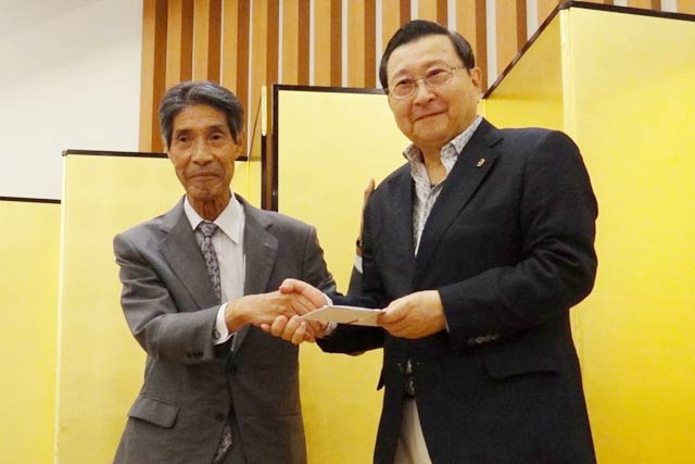 加藤紋次郎さんから加藤敏敦会長に寄付を手渡す