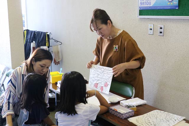 マンホールの拓本の彩色を指導する土田さん