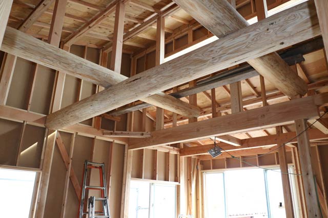 構造内覧会を開く中進住宅が建築中の住宅に施された骨太な丸太の梁