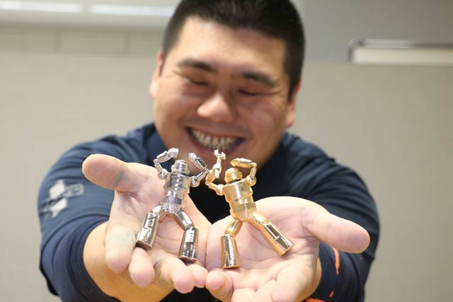 高秋化学が特許出願中の3Dプリンターの造形品にメッキを施す技術でメッキした燕三条ものづくりメッセのキャラクター「TSUBASAN-ROBO」を手に高橋社長