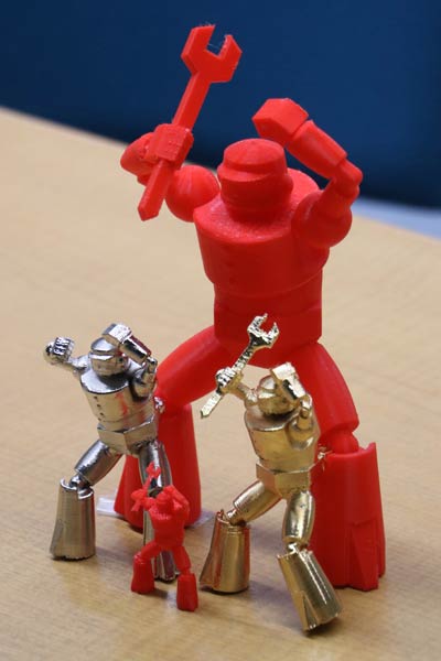 3Dプリンターで出力した赤い造形品とそれにメッキを施したもの