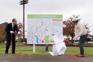 三条中央ライオンズクラブが案内看板とベンチを設置した三条市総合運動公園で若山副市長(左)と三条中央ライオンズの土田会場で案内看板の除幕