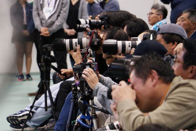 最前列で一眼レフカメラを構えたファン