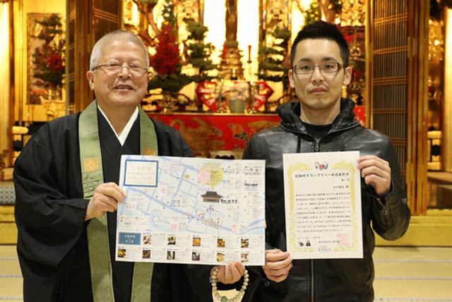 「超難解スタンプラリー」のコンプリート第1号となった員大竹昌弘さん(右)と表彰状を手渡した森田輪番