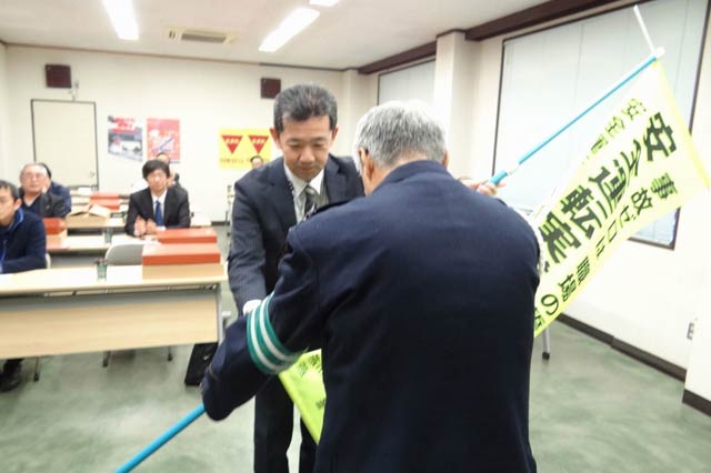 大光銀行燕支店の安全運転管理者、岡村正弘副支店長が交通安全旗を燕署交通課長に手渡す