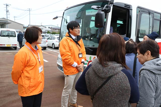バスの車内で次に向かう工場について話す土橋さん