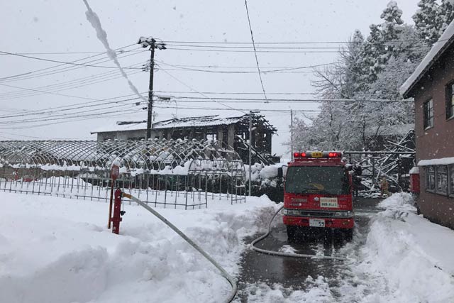 写真奥が火災現場で付近は腰くらいの高さまで雪が積もっている