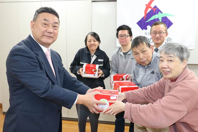 利用者にクリスマスケーキを手渡すローソン燕杣木店の長岡オーナー