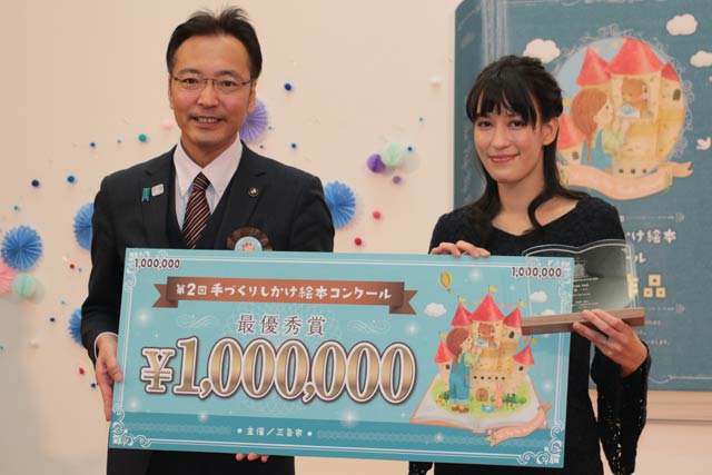 国定市長から賞金100万円のプレートを受け取る山端マリーさん
