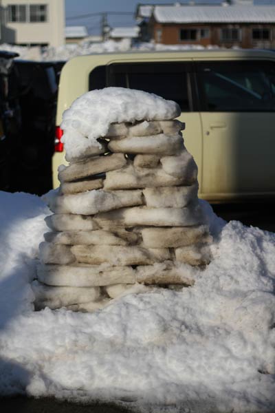 圧雪はぎと思われる積み上げられた平べったい汚れた雪の塊