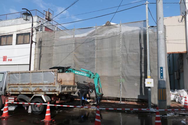 防護ネットが張られた旧武田文祥堂の空き店舗前では16日も除雪が行われた