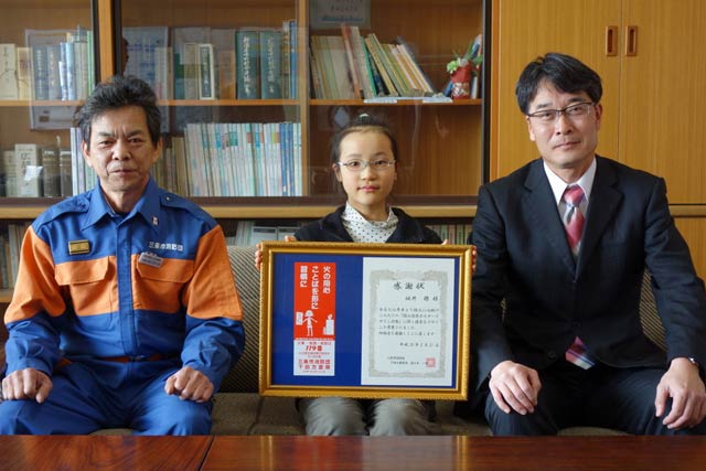 左から三条市消防団下田方面隊の佐々木方面隊長、ちらしの挿し絵に作品が採用された飯田小4年坂井さん、飯田小の黒田校長