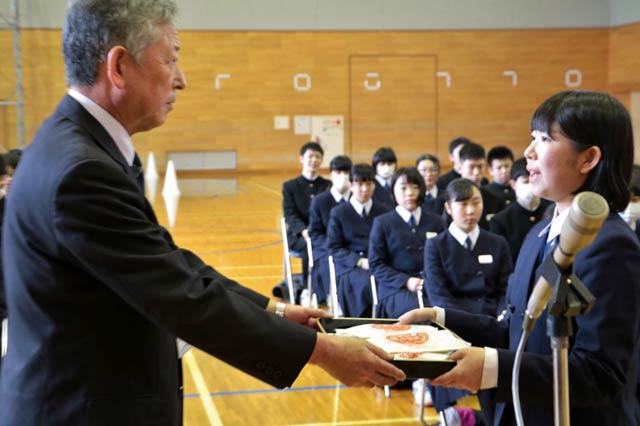 Jにいがた南蒲の押野見経営管理委員会副会長から3年生代表の大倉生徒会副会長に「難関突破米」を手渡す