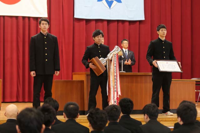 県央工業高校の平成29年度新潟県高等学校体育連盟スポーツ年間最優秀校の授賞式、登壇した賞状やトロフィーを受けた左から弓道部長の2年高野翔吾さん、ウエイトリフティング部長の3年鈴木海聖さん、レスリング部長の3年鈴木一成さん、