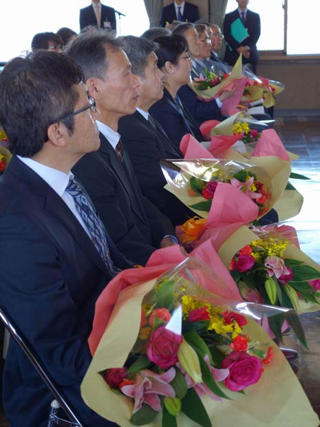 花束を抱いて席について国定市長の話を聞く退職者