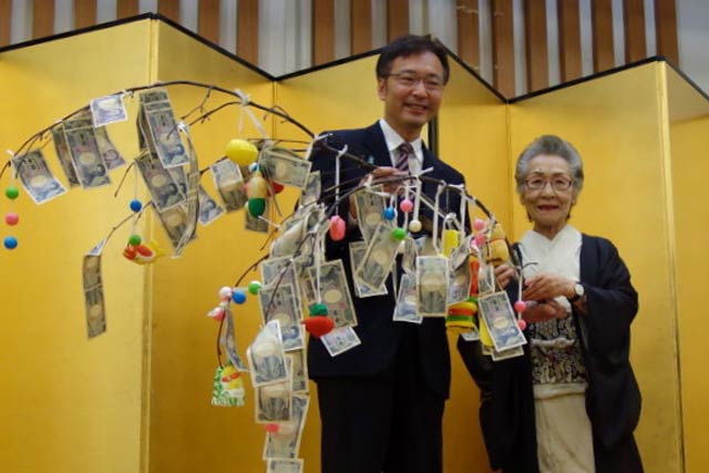 国定市長にまゆ玉飾りにぶら下がった善意を手渡すマンマの五十嵐さん