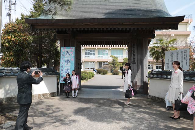 燕東小学校の入学式絵校門の前で写真を撮る新一年生と保護者