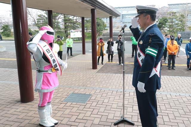 出発式で一日交通課長の委嘱状とたすきを受けて渋谷署長に敬礼するメテオレンジャーのピンク