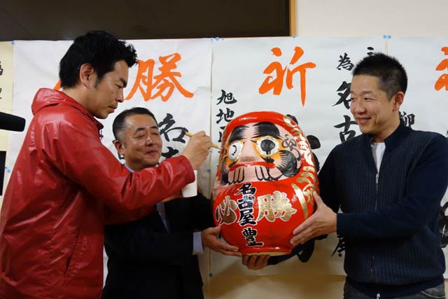 「手が震える」と言いながらだるまの目入れをする名古屋氏(左)