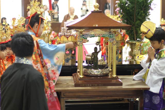 灌仏式で釈迦の誕生像に甘茶をかける