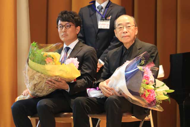 花束を受けたフレームの石川さん(左)と小椋佳さん