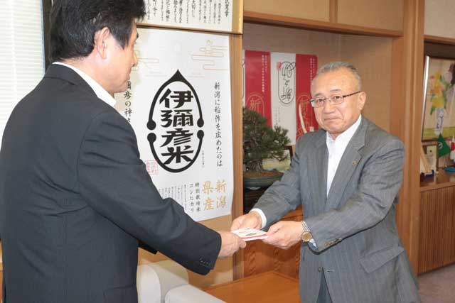 弥彦小の大石校長（左）に弥彦村防犯組合会長として防犯ブザーの目録を手渡す小林村長