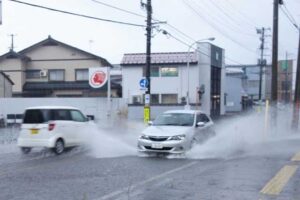 三条市興野1付近の第1産業道路が冠水して大きな水しぶきを上げて走る車