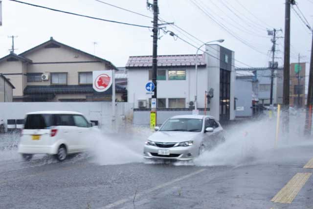 三条市興野1付近の第1産業道路が冠水して大きな水しぶきを上げて走る車