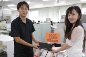 諸橋福祉課長(右)に義援金を手渡す諏訪田製作所の水沼さん