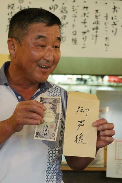 「御声援」と書いた袋に入った5千円を受けた長谷川さん