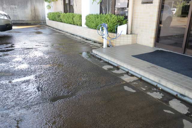 坂井達三商店前駐車場は消雪パイプの水を出して打ち水