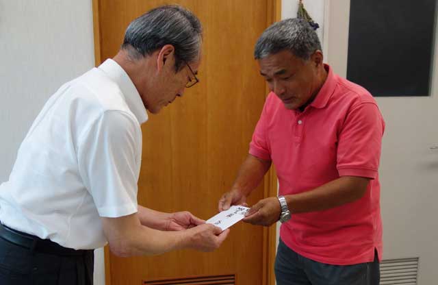 三条市社会福祉協議会の渡辺事務局長(左)に大崎コミュニティ「どんぐりころころ大崎」の寄付を手渡す高橋会長