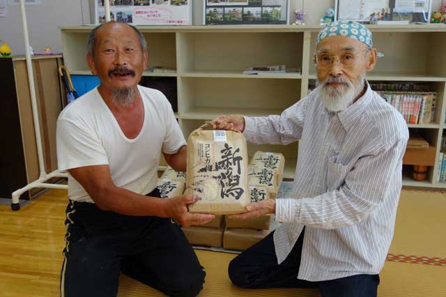 渡辺さん(左)から佐竹さんに新米を手渡した