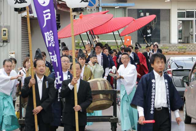 7張の朱傘を連ねて戸隠神社の社殿再建百年記念大祭の行列