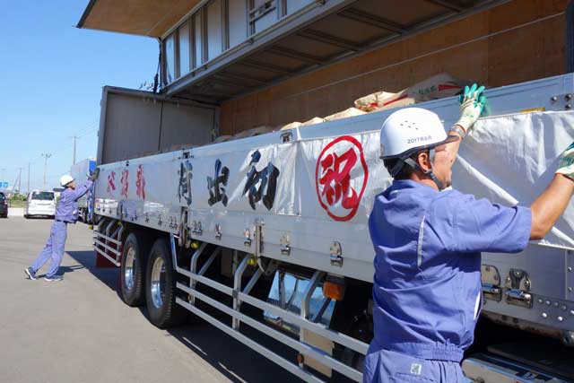 トラックのアオリに「祝　初出荷　新潟米」の横断幕を張る