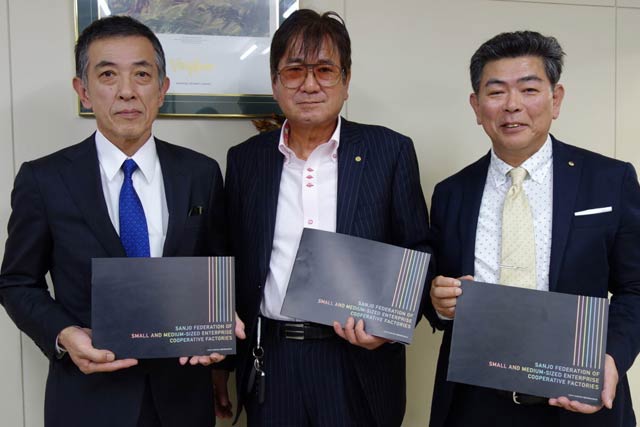 三条中小企業共同工場協同組合連合会50周年の記念誌を手に左から小林さん、山村さん、五十嵐さん