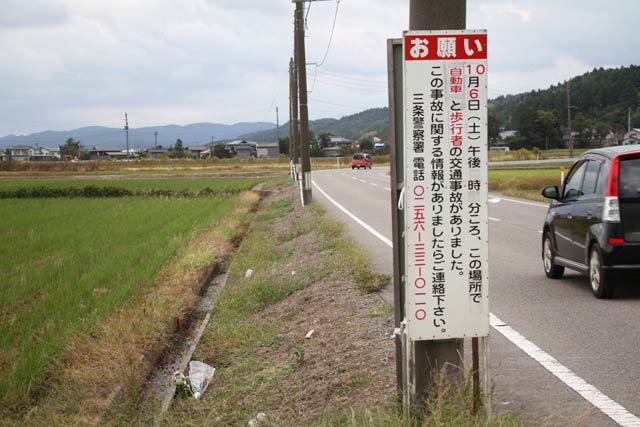 事故現場には三条署が事故の情報提供を求める看板が立ち花が手向けられていた