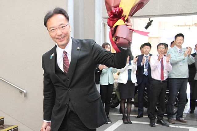 花束を掲げて職員の歓迎にこたえる国定市長