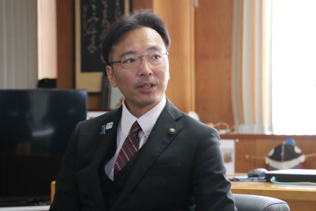 花束を掲げて職員の歓迎にこたえる国定市長