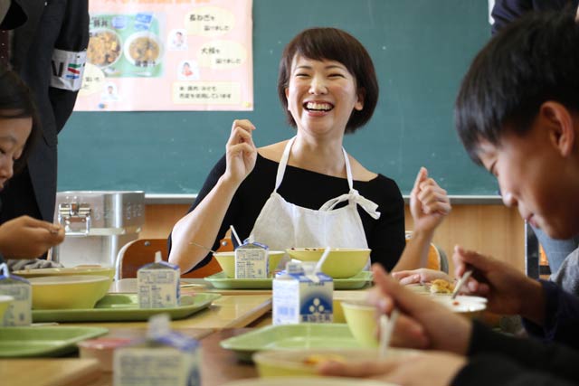 燕私立燕西小学校で児童と一緒に新メニューを食べる村山瑛子さん
