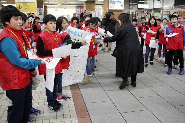 燕三条駅で分北米を配布する分水北小5年生