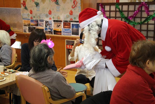 特別養護老人ホーム「分水の里」で開かれたクリスマス会忘年会でサンタクロースにふんした分水商工会青年部員が利用者にクリスマスプレゼントを配布