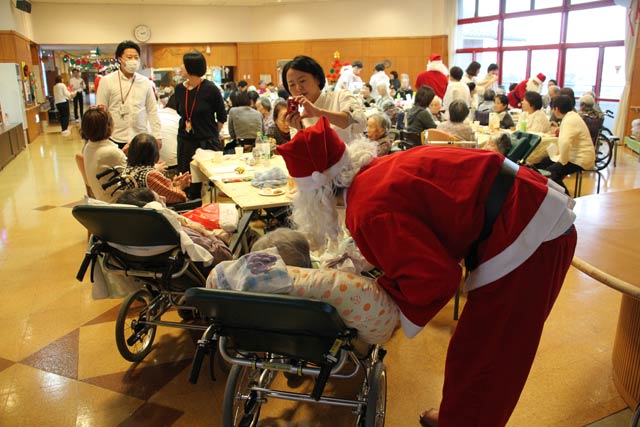 特別養護老人ホーム「分水の里」で開かれたクリスマス会忘年会でサンタクロースにふんした分水商工会青年部員が利用者にクリスマスプレゼントを配布