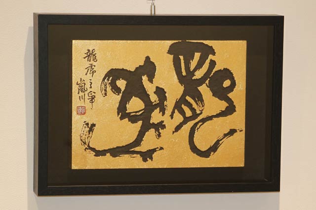 第37回日本刻字展で日本刻字協会理事長賞を受けた金子さんと会場で展示している金子さんの作品