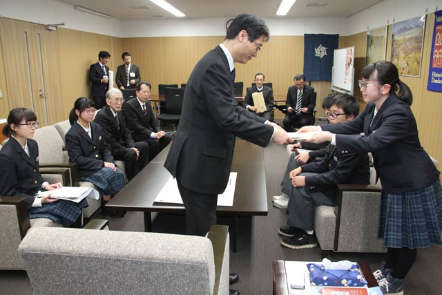 糸半プロジェクトで作った冊子を鈴木市長に手渡す