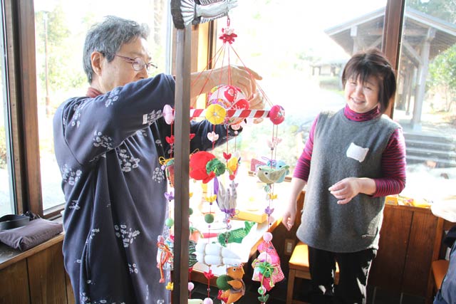 生徒のつるし雛の最後の仕上げに手を貸す講師の清水さん(左)