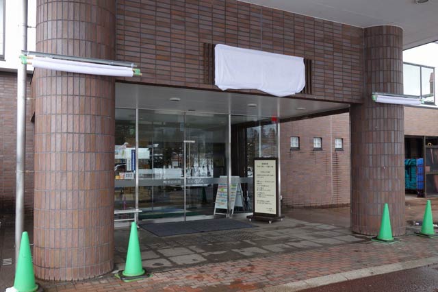 正面玄関に設置した新しいロゴマークの看板には白布がかけてある